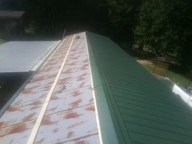 Old rusted panels beside newly installed green metal roofing — Wind Damage Roof Repair by Roofing Brothers in Glenview