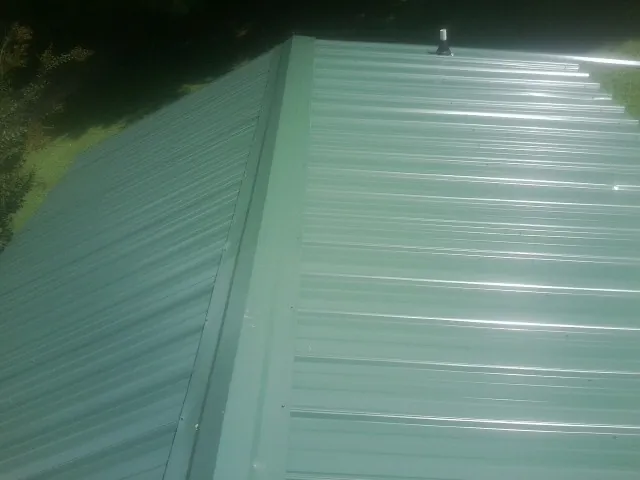 New green metal panels meeting at the ridge of a roof — Flat Roof Repair work by our crew in Glenview