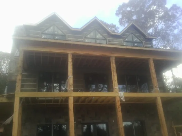 Dormers and porch framing on a large log home under construction — Roof Coating work by our crew in Glenview