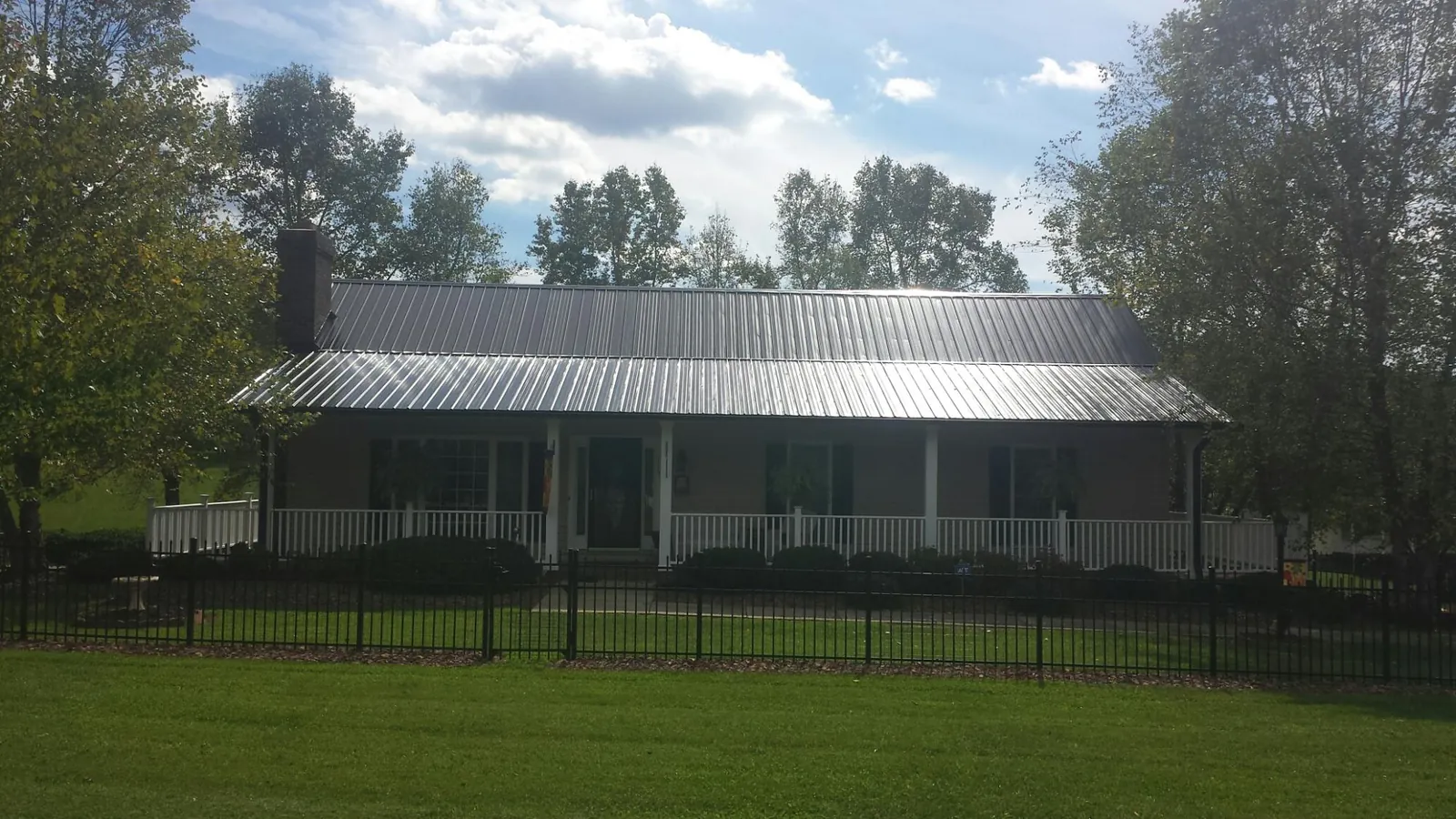 Gray metal roof on a brick ranch with a full width front porch — Gutter Guard Installation work by our crew in Glenview