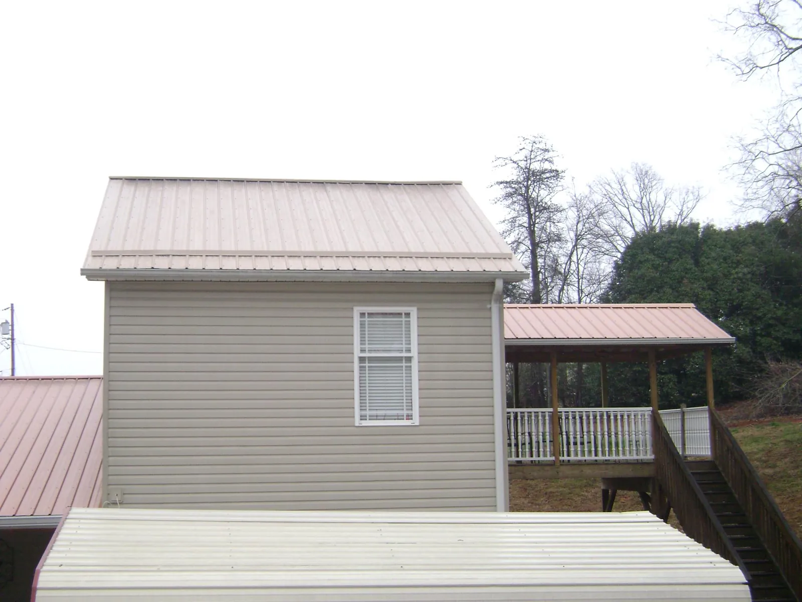 Tan metal roofs on a two story addition and attached porch, from a Roof Replacement job in Glenview