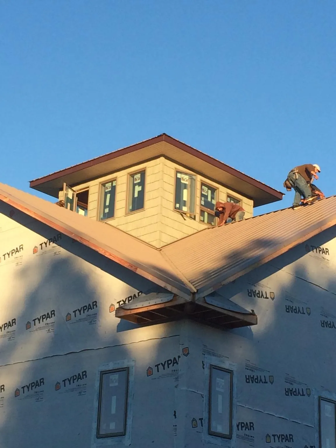 Roofers working around a rooftop cupola on a new metal roof at sunset — Roof Waterproofing in Glenview by Roofing Brothers